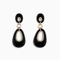 The Eclipse 14K Yellow Gold Onyx and Diamond Drop Earrings feature elegant black oval onyx, diamond accents around oval cutouts, and gold details, all beautifully displayed on a white background.