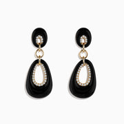 The Eclipse 14K Yellow Gold Onyx and Diamond Drop Earrings feature elegant black oval onyx, diamond accents around oval cutouts, and gold details, all beautifully displayed on a white background.
