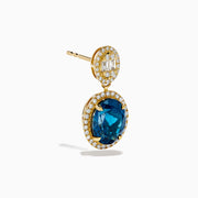 The 14K Yellow Gold Blue Topaz and Diamond Oval Drop Earrings feature large oval blue topaz gemstones encircled by white diamonds, with a sparkling diamond cluster above each stone for an elegant drop design.