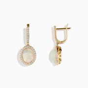 The 14K Yellow Gold Opal and Diamond Drop Earrings feature oval opal gemstones framed by sparkling diamonds, with additional diamond accents on the gold hoops and drops, creating an elegant look against a white background.