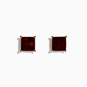A pair of 14K Rose Gold Garnet Stud Earrings, featuring square-cut deep red garnets in gold prongs, displayed on a plain white background.