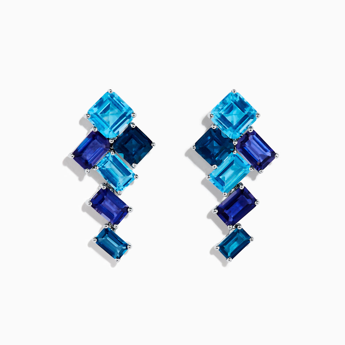The 14K White Gold Blue Topaz and Iolite Earrings feature square and rectangular blue gemstones arranged diagonally, creating a striking and elegant accessory.