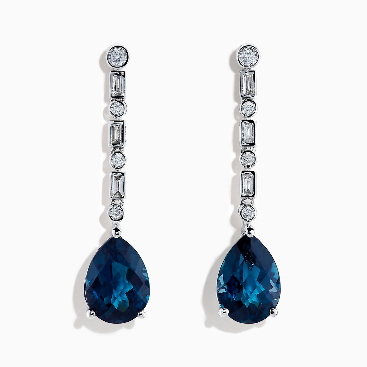 The 14K White Gold Blue Topaz and Diamond Linear Drop Earrings feature large teardrop-shaped blue topaz gems with a vertical row of round and rectangular diamonds set above each stone.