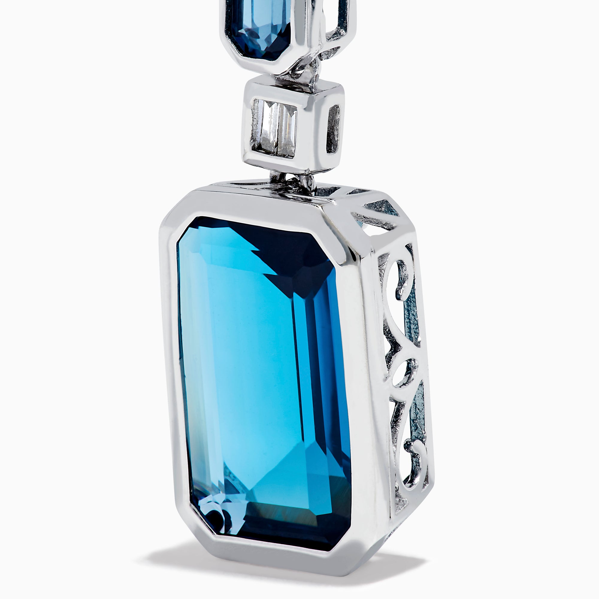 14K White Gold Blue Topaz and Diamond Geometric Drop Earrings featuring rectangular deep blue topaz gems, each accented by a smaller blue stone and a baguette-cut diamond, displayed against a white background.