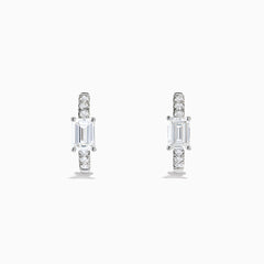 Lab Grown Diamond Emerald-Cut Huggie Earrings in 14K White Gold showcase rectangular center stones accented by small round diamonds, elegantly set and displayed against a plain white background.