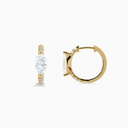 Lab Grown Diamond Marquise Huggie Earrings in 14K Yellow Gold, each showcasing a central round diamond and smaller accent diamonds along the vertical sides, displayed on a plain white background.
