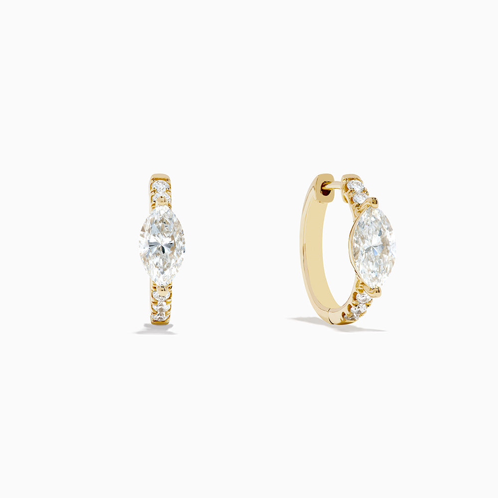 Lab Grown Diamond Marquise Huggie Earrings in 14K Yellow Gold, each showcasing a central round diamond and smaller accent diamonds along the vertical sides, displayed on a plain white background.