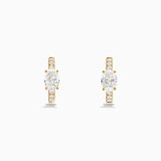 Lab Grown Diamond Oval Huggie Earrings in 14K Yellow Gold, each with a central oval lab diamond and smaller round lab diamonds on the front, are shown against a plain white background.