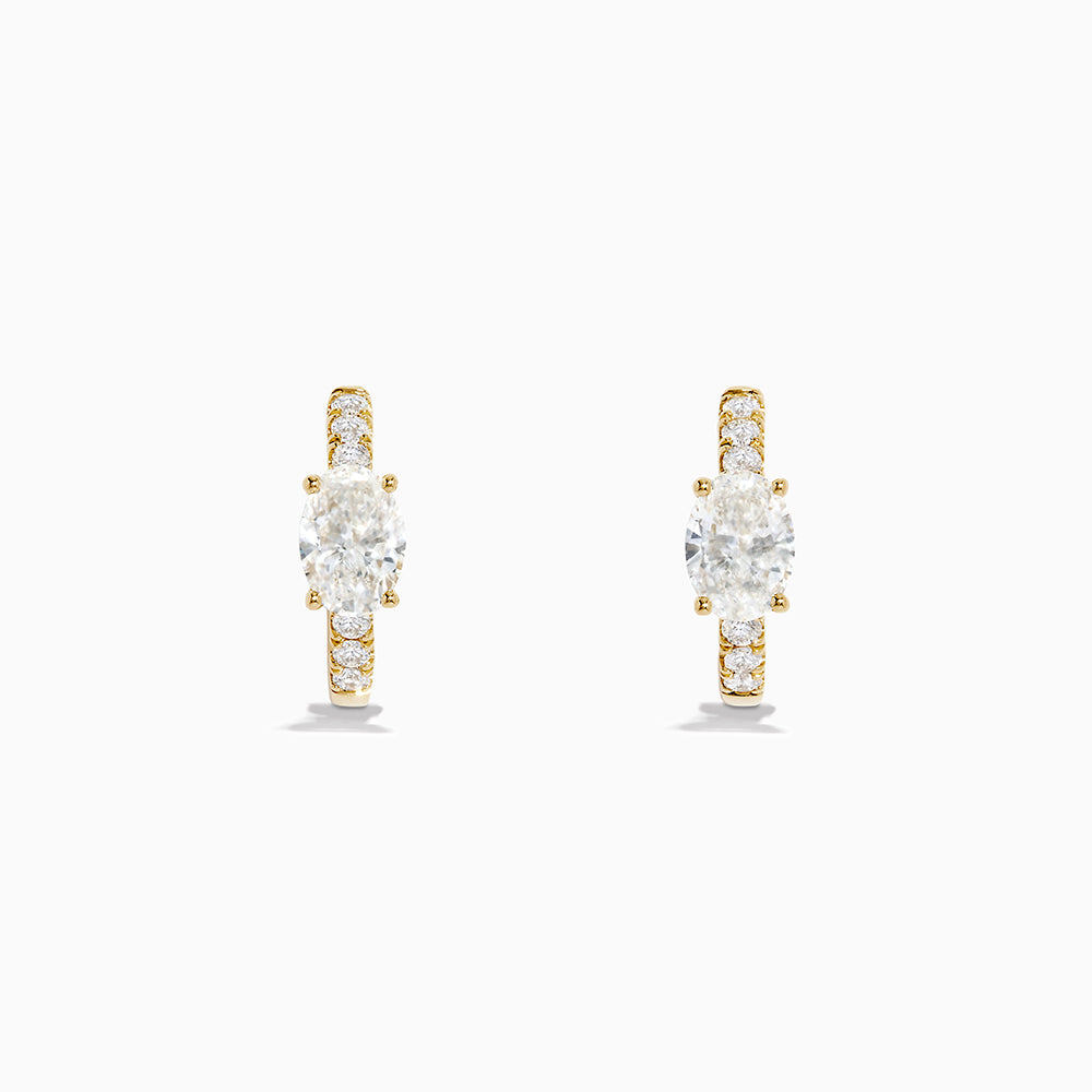 Lab Grown Diamond Oval Huggie Earrings in 14K Yellow Gold, each with a central oval lab diamond and smaller round lab diamonds on the front, are shown against a plain white background.