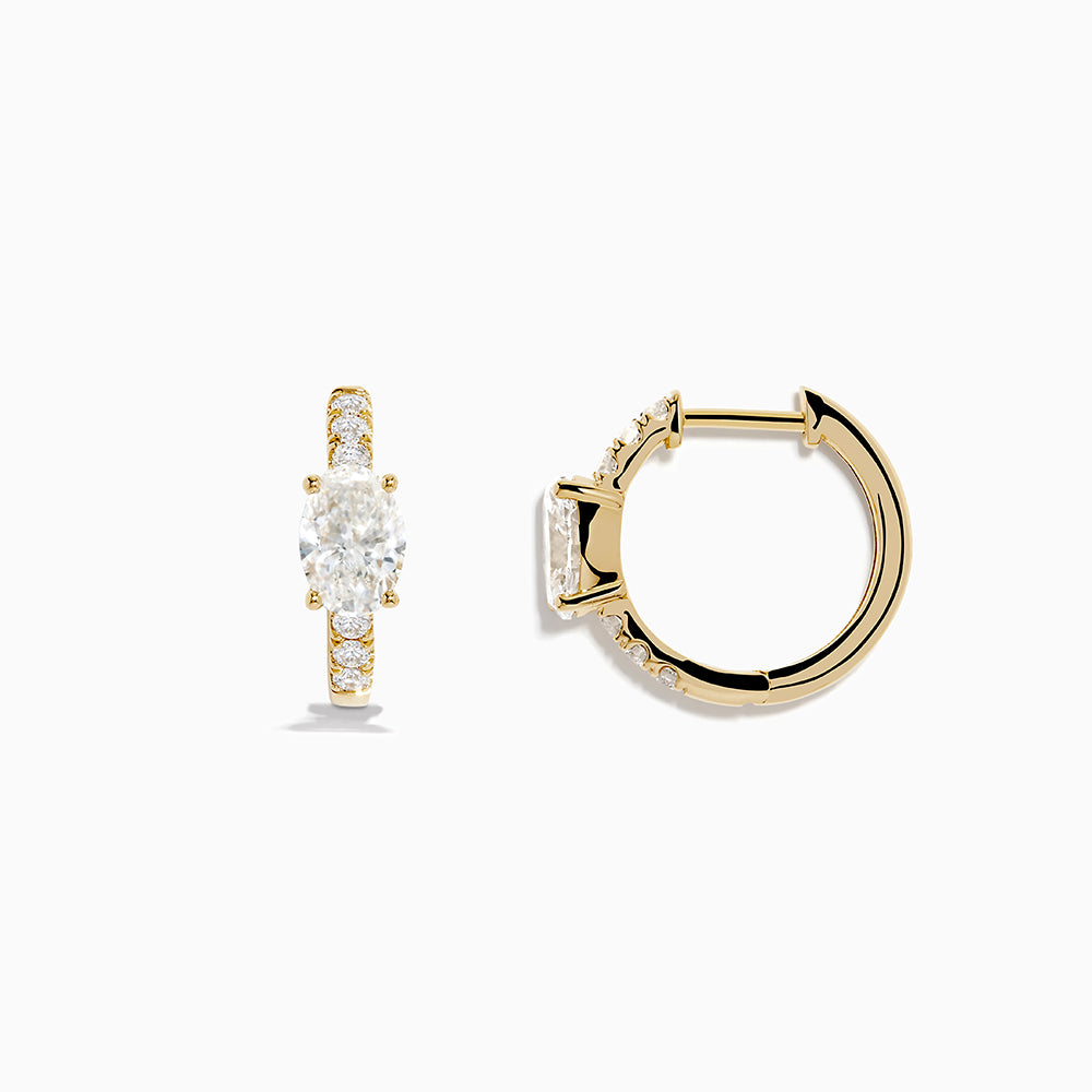 Lab Grown Diamond Oval Huggie Earrings in 14K Yellow Gold, each with a central oval lab diamond and smaller round lab diamonds on the front, are shown against a plain white background.