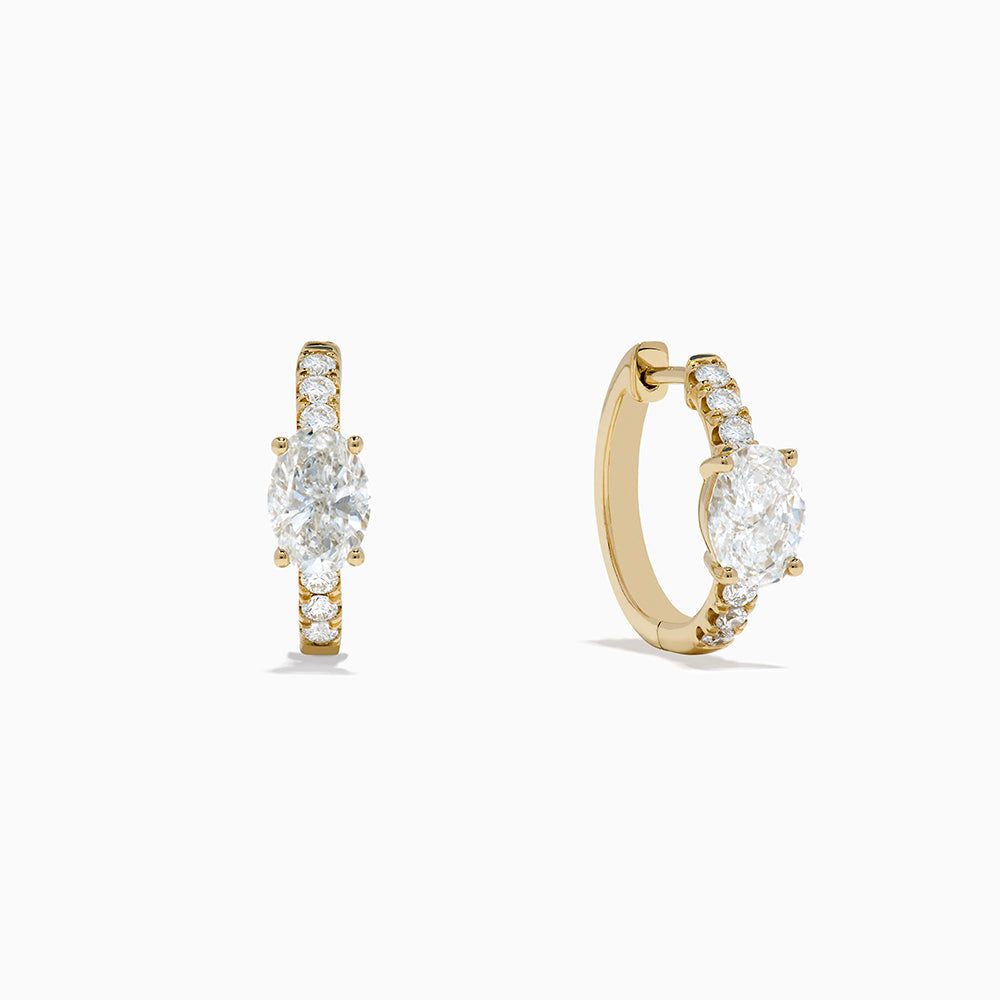 Lab Grown Diamond Oval Huggie Earrings in 14K Yellow Gold, each with a central oval lab diamond and smaller round lab diamonds on the front, are shown against a plain white background.