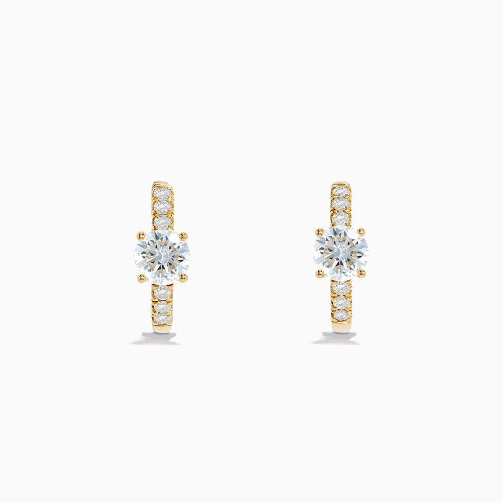 The Lab Grown Diamond Round Huggie Earrings in 14K Yellow Gold feature a central round lab diamond accented by a row of smaller lab diamonds, all set in sleek yellow gold and displayed on a white background.