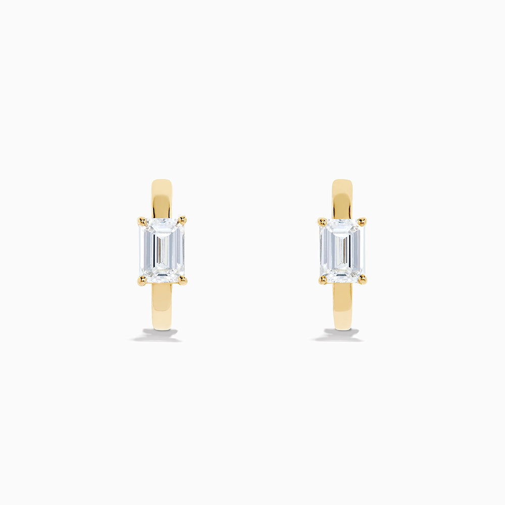 A pair of Lab Grown Diamond Emerald-Cut Huggie Earrings in 14K Yellow Gold is shown on a plain white background, each earring featuring a vertically set emerald-cut lab grown diamond at the center.