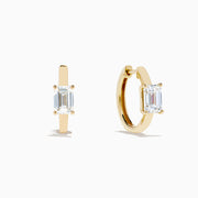 A pair of Lab Grown Diamond Emerald-Cut Huggie Earrings in 14K Yellow Gold is shown on a plain white background, each earring featuring a vertically set emerald-cut lab grown diamond at the center.
