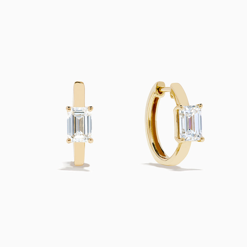 A pair of Lab Grown Diamond Emerald-Cut Huggie Earrings in 14K Yellow Gold is shown on a plain white background, each earring featuring a vertically set emerald-cut lab grown diamond at the center.