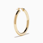 The 14K Yellow Gold Hollow Tube Hoops are sleek, polished earrings shown side by side against a white background, featuring classic yellow gold in a timeless hoop design with clasps at the top.