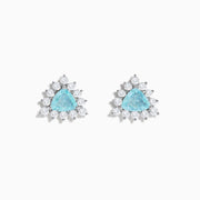 A pair of 18K white gold GIA certified Paraiba and diamond stud earrings with triangular blue gems surrounded by a halo of small diamonds, set in silver, displayed on a white background.