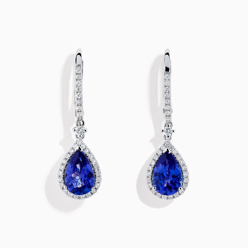 The Nahla 14K White Gold Tanzanite and Diamond Dangle Halo Earrings feature teardrop-shaped tanzanite stones surrounded by sparkling diamonds, set in elegant white gold and displayed against a white background.