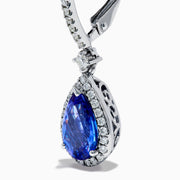 The Nahla 14K White Gold Tanzanite and Diamond Dangle Halo Earrings feature teardrop-shaped tanzanite stones surrounded by sparkling diamonds, set in elegant white gold and displayed against a white background.