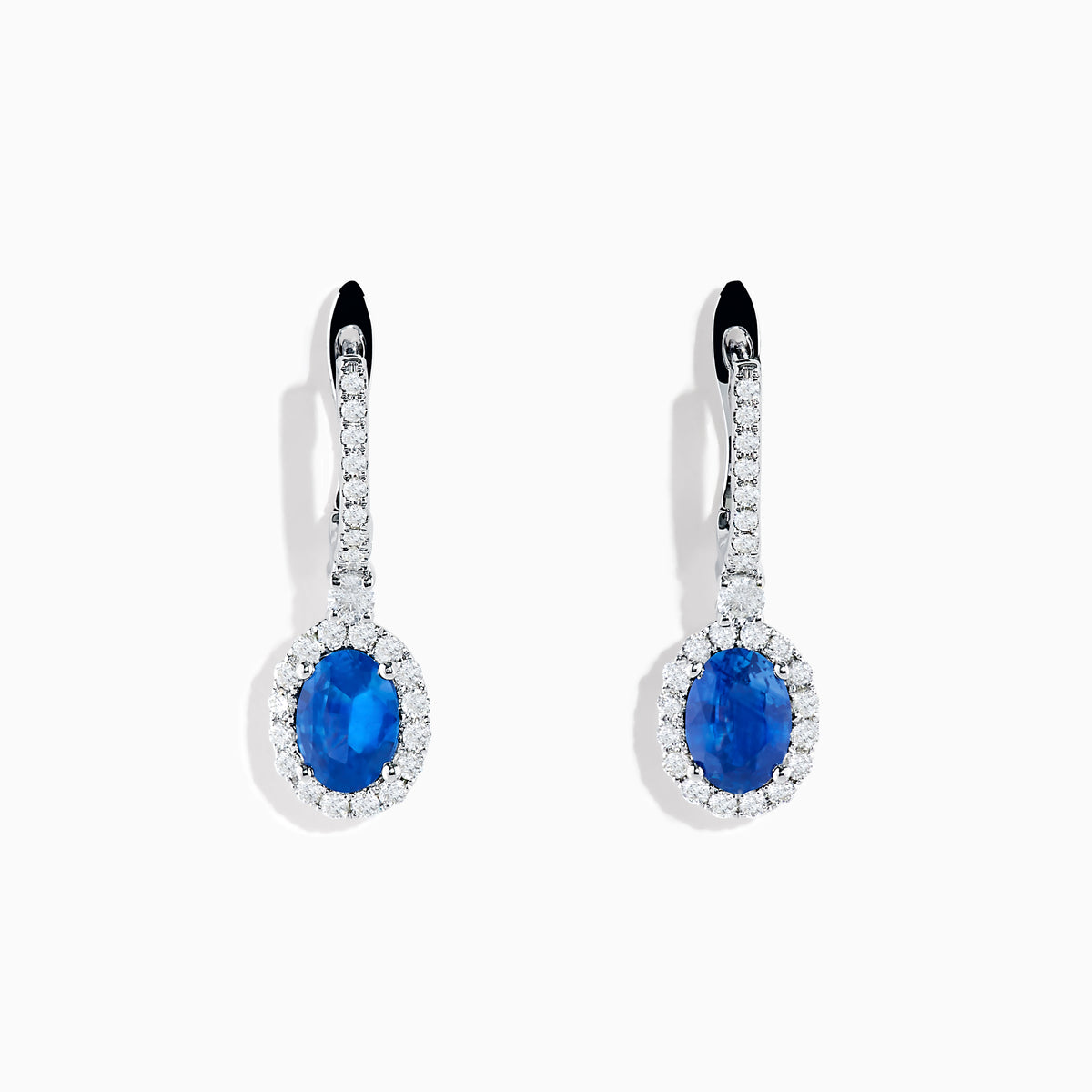 Introducing the 14K White Gold Oval Blue Sapphire and Diamond Drop Earrings, featuring striking oval blue sapphires surrounded by sparkling diamonds in a vertical drop design, set in elegant 14K white gold with diamond-accented hooks.