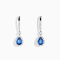 The 14K White Gold Pear Shape Blue Sapphire and Diamond Drop Earrings feature teardrop-shaped sapphires surrounded by white diamonds, set in elegant white gold, shown on a white background.