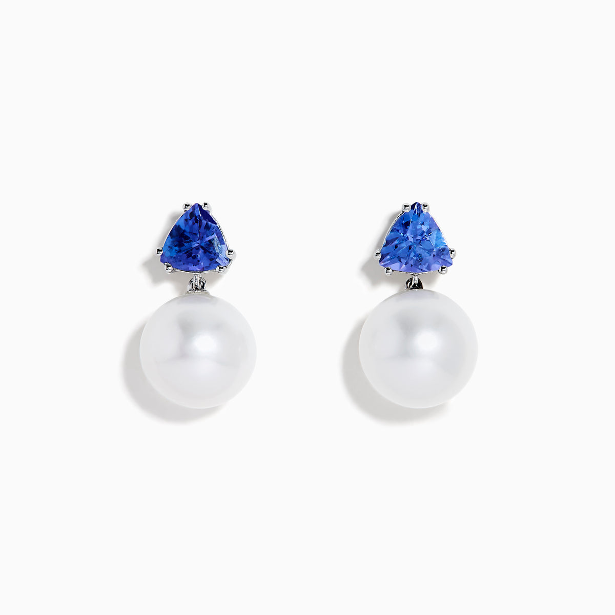 The Nahla 14K White Gold Fresh Water Pearl and Tanzanite Earrings feature round white pearls suspended below triangular blue tanzanite gemstones, set in white gold, displayed on a white background.