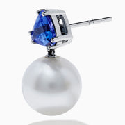 The Nahla 14K White Gold Fresh Water Pearl and Tanzanite Earrings feature round white pearls suspended below triangular blue tanzanite gemstones, set in white gold, displayed on a white background.