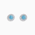 Lab Grown Blue Diamond Halo Stud Earrings in 14K White Gold feature round lab grown blue diamonds encircled by halos of white diamonds, set in a circular design on a white background.