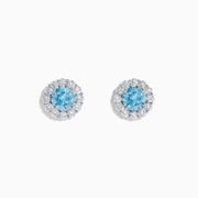 Lab Grown Blue Diamond Halo Stud Earrings in 14K White Gold feature round lab grown blue diamonds encircled by halos of white diamonds, set in a circular design on a white background.