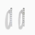 A stunning pair of 14K White Gold Diamond Inside Out 1" Hoop Earrings, each adorned with a row of brilliant round white diamonds, displayed vertically against a white background with soft shadows. These hoop earrings are designed in an inside out style, ensuring each diamond sparkles beautifully from every angle.