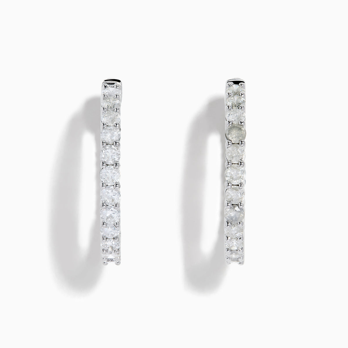 A stunning pair of 14K White Gold Diamond Inside Out 1" Hoop Earrings, each adorned with a row of brilliant round white diamonds, displayed vertically against a white background with soft shadows. These hoop earrings are designed in an inside out style, ensuring each diamond sparkles beautifully from every angle.