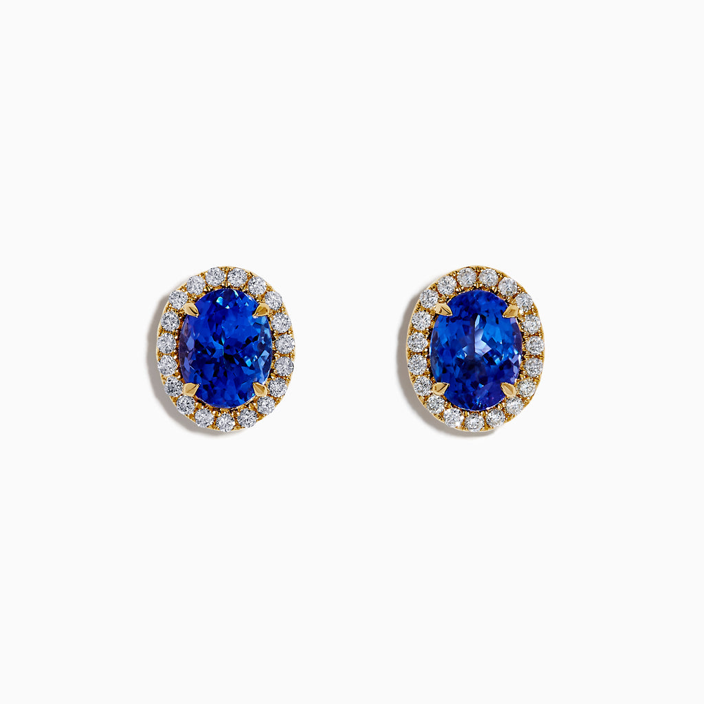 The Nahla 14K Yellow Gold Tanzanite and Diamond Stud Earrings feature oval blue tanzanites each encircled by a halo of diamonds, beautifully displayed on a white background.