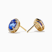 The Nahla 14K Yellow Gold Tanzanite and Diamond Stud Earrings feature oval blue tanzanites each encircled by a halo of diamonds, beautifully displayed on a white background.