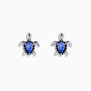 A pair of 925 Silver Tanzanite and Diamond Turtle Stud Earrings, featuring turtle shapes with blue tanzanite centers, displayed on a white background.