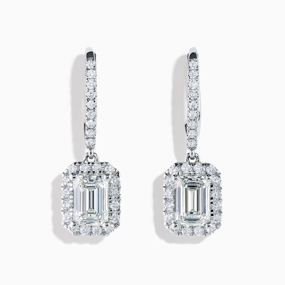 The Lab Grown Diamond Emerald Cut Dangle Earrings in 14K White Gold showcase emerald cut lab grown centers with a halo of round diamonds and diamond-encrusted hooks, elegantly presented against a white background.