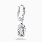 The Lab Grown Diamond Emerald Cut Dangle Earrings in 14K White Gold showcase emerald cut lab grown centers with a halo of round diamonds and diamond-encrusted hooks, elegantly presented against a white background.