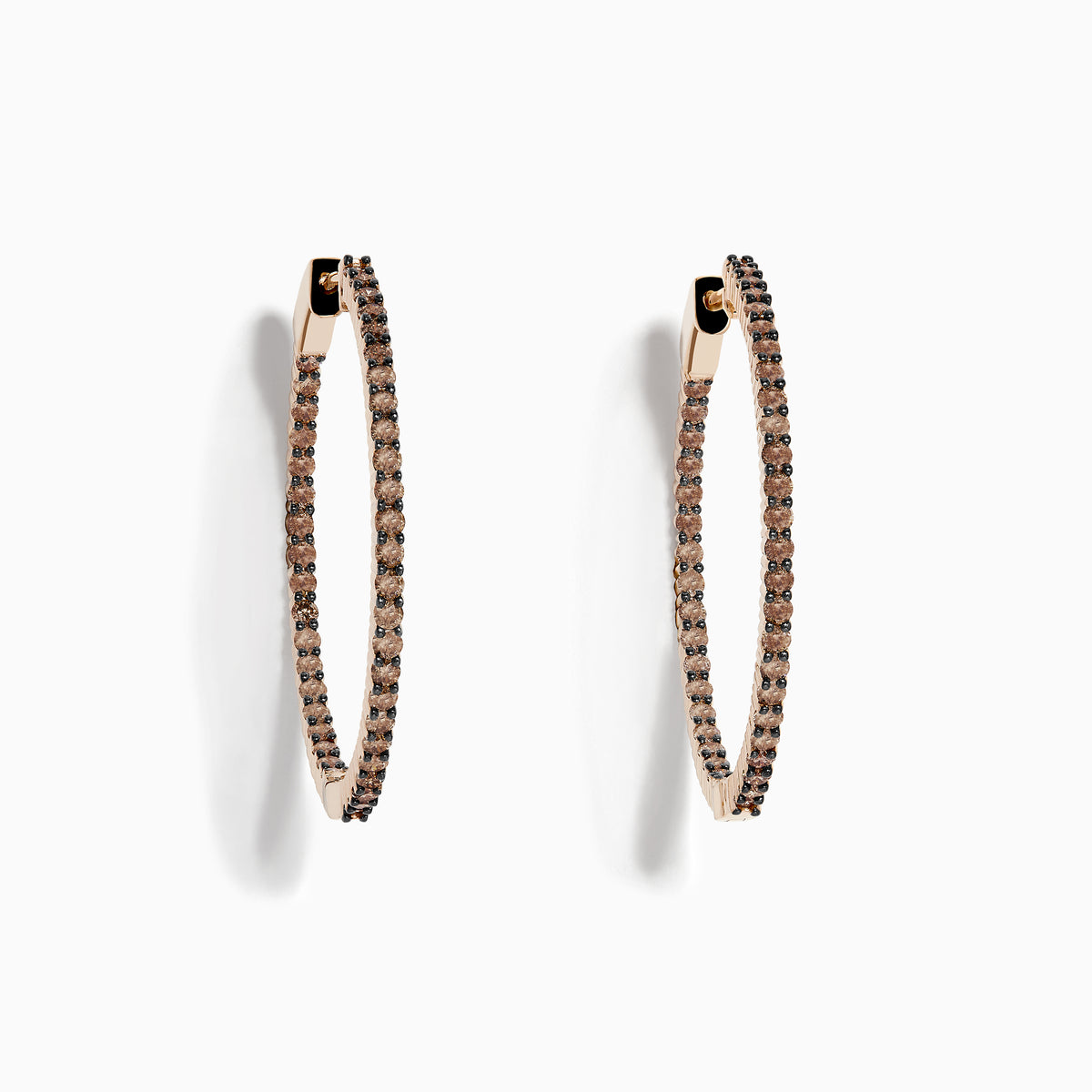 The 14K Rose Gold Brown Diamond 1.5 Inch Hoop Earrings, featuring slim vertical hoops with dark brown diamonds, are photographed against a plain white background, casting soft oval-shaped shadows to the left.