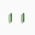 The 14K Yellow Gold Emerald Huggie Earrings feature small gold hoops set with bright green gemstones, crafted in 14K yellow gold and showcased against a white background.