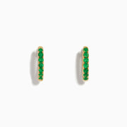 The 14K Yellow Gold Emerald Huggie Earrings feature small gold hoops set with bright green gemstones, crafted in 14K yellow gold and showcased against a white background.