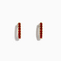 Ruby Royale 14k Yellow Gold Ruby Huggie Earrings: Small yellow gold hoops featuring a single row of red rubies, elegantly displayed against a plain white background.