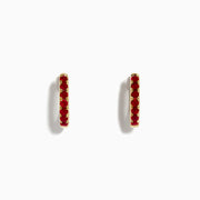 Ruby Royale 14k Yellow Gold Ruby Huggie Earrings: Small yellow gold hoops featuring a single row of red rubies, elegantly displayed against a plain white background.