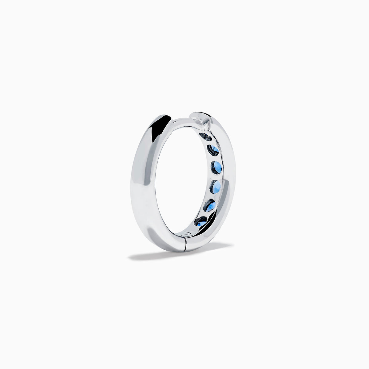 The Royale Bleu 14K White Gold Sapphire Huggie Earrings feature a row of round blue sapphires and are displayed against a white background.