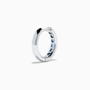 The Royale Bleu 14K White Gold Sapphire Huggie Earrings feature a row of round blue sapphires and are displayed against a white background.
