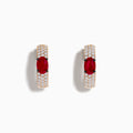 These 14K Rose Gold Ruby and Diamond Huggie Hoop Earrings feature a central oval ruby surrounded by rows of sparkling diamonds, creating a stunning shine against any background.