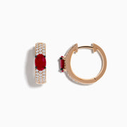These 14K Rose Gold Ruby and Diamond Huggie Hoop Earrings feature a central oval ruby surrounded by rows of sparkling diamonds, creating a stunning shine against any background.