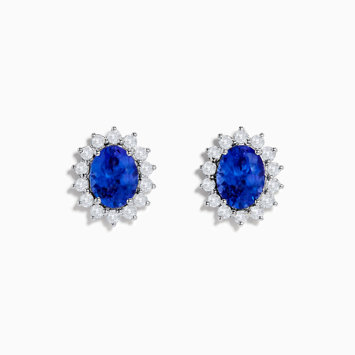 The Nahla Siri 14K White Gold Tanzanite and Diamond Earrings feature oval tanzanite stones surrounded by a halo of sparkling diamonds, elegantly set in white gold and displayed on a white background.