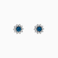 Bella Bleu 14K White Gold Blue and White Diamond Earrings, 1.20 TCW, feature a central round blue stone encircled by sparkling white diamonds in a flower-inspired design, displayed on a white background.