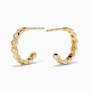 D'Oro 14K Yellow Gold Bezel Set Diamond Mini Hoop Earrings feature round diamonds in bezel settings along the front, alternating with gold, shown on a white background.