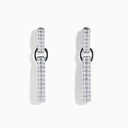 The Pave 14K White Gold Diamond Interlocking Hoop Earrings include one straight, diamond-encrusted bar and one open, asymmetrical, diamond-lined hoop, creating a modern mismatched look against a white background.