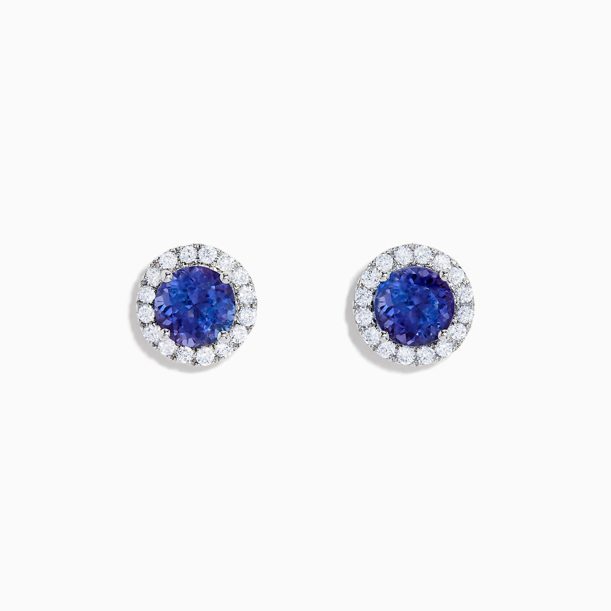 The Nahla 14K White Gold Tanzanite and Diamond Stud Earrings feature round deep blue tanzanite centers, each surrounded by a halo of sparkling white diamonds, beautifully set in 14K white gold against a crisp white background.
